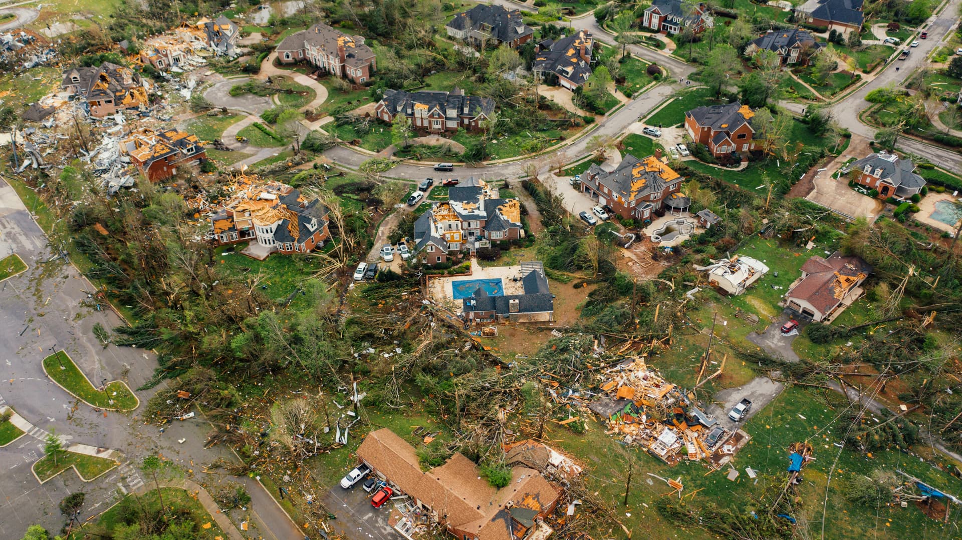 Aerial view of a residential neighborhood with widespread storm damage and debris